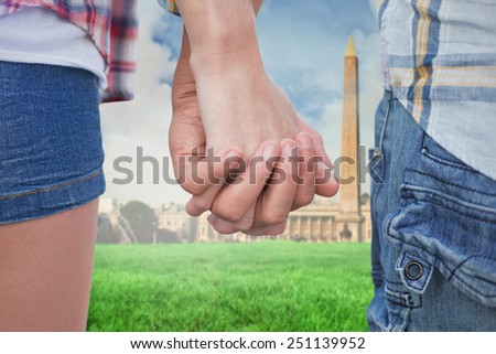 Couple in check shirts and denim holding hands against paris under cloudy sky