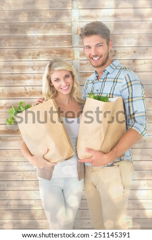Attractive couple holding their grocery bags against light glowing dots design pattern