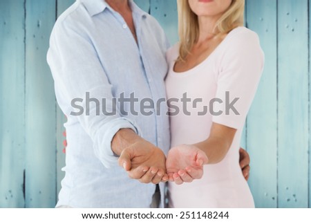 Happy couple holding their hands out against wooden planks