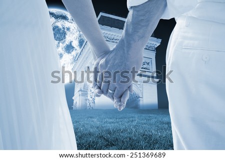 Bride and groom holding hands close up against bright moon over arc de triomph