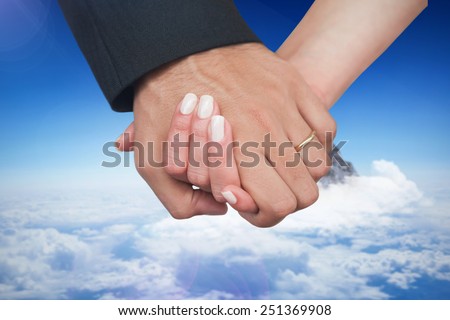 Newlyweds holding hands close up against mountain peak through the clouds