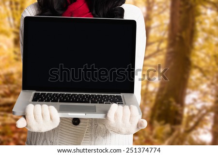 Woman holding a laptop computer against tranquil autumn scene in forest