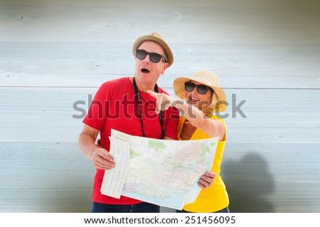 Happy tourist couple using map against bleached wooden planks background