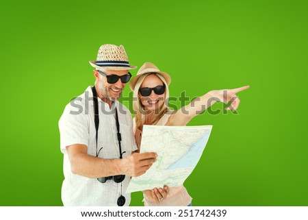 Happy tourist couple using map and pointing against green vignette