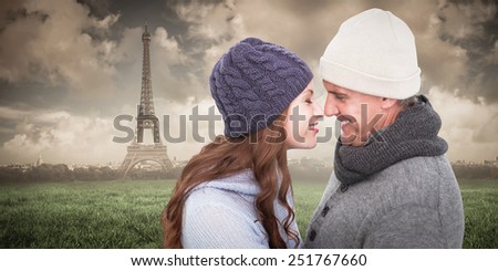Couple in warm clothing facing each other against paris under cloudy sky