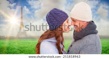 Couple in warm clothing facing each other against eiffel tower
