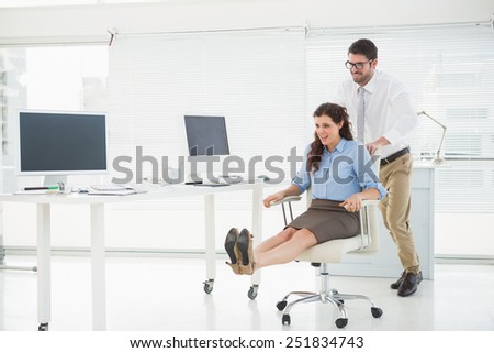Happy team playing together with swivel chair in the office