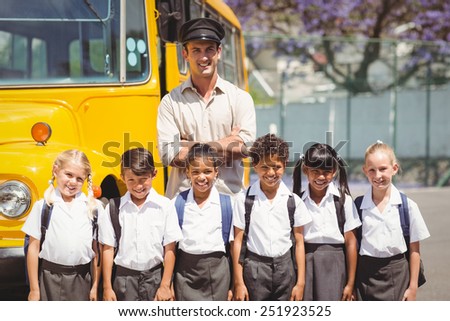 Cute pupils with their school bus driver outside the elementary school