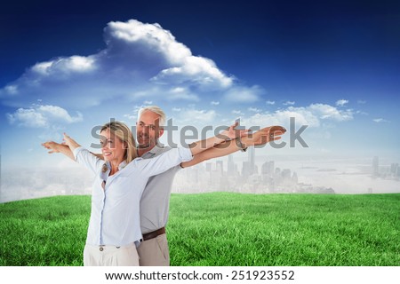 Happy couple standing with arms outstretched against sunny day by the river