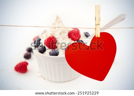 Heart hanging on line against jar of blueberries and raspberries in a whipped cream