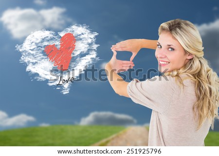 Attractive young blonde framing with her hands against cloud heart