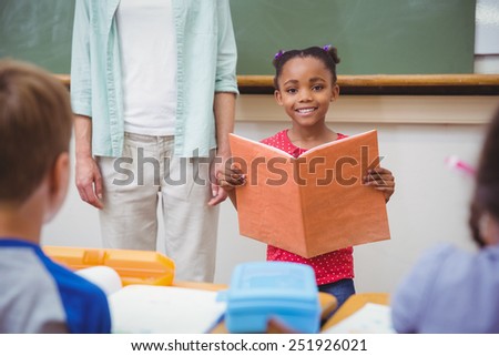 Cute pupils smiling at camera in classroom at the elementary school