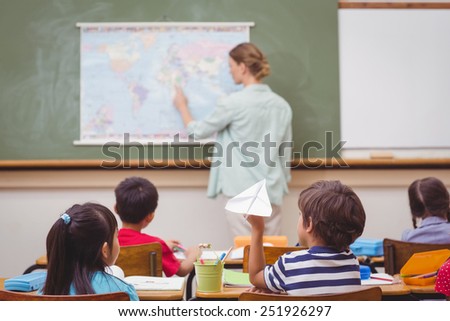 Naughty pupil about to throw paper airplane in class at the elementary school