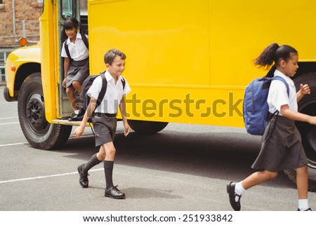 Cute schoolchildren getting off the school bus outside the elementary school