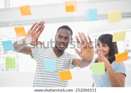 Smiling coworkers brainstorming with sticky notes in the office