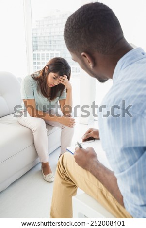 Therapist taking notes on his upset patient at therapy session