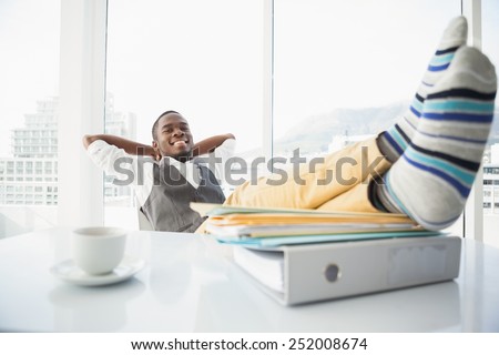 Relaxed businessman sitting in his chair with feet up in his office