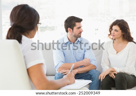Couple sitting on sofa talking with their therapist in the office