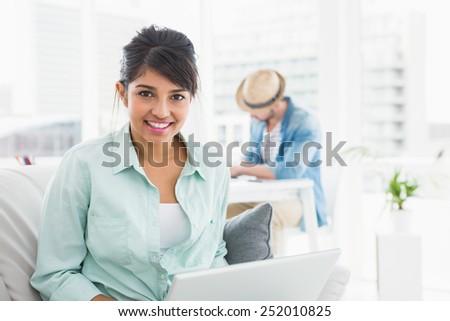 Cheerful businesswoman on couch looking at camera in the office