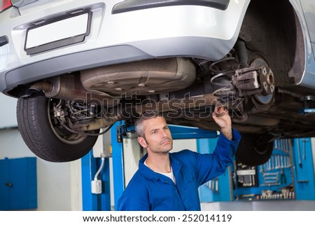 Mechanic examining under the car at the repair garage