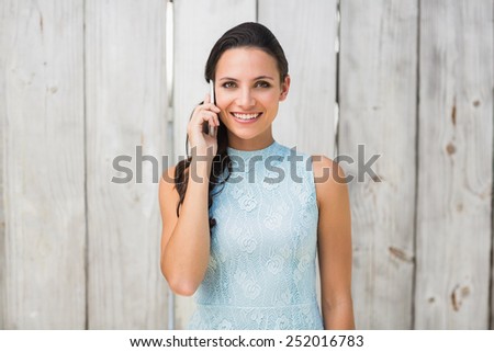 Stylish brunette on the phone against bleached wooden fence