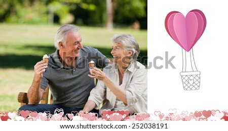 Senior couple eating an ice cream on a bench against heart hot air balloon