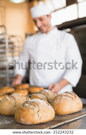 Happy baker taking out fresh bagels in the kitchen of the bakery