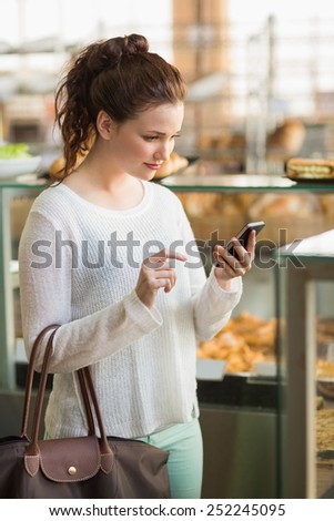 Pretty brunette sending a text at the bakery