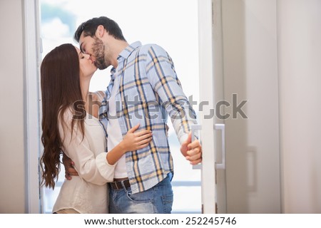 Young couple kiss as they open front door in their new home