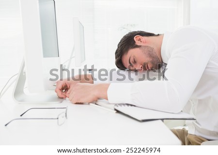 Tired businessman sleeping on keyboard in his office
