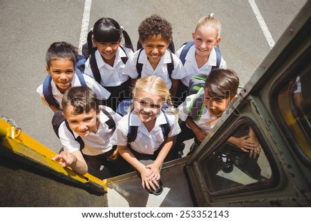 Cute schoolchildren getting on school bus outside the elementary school