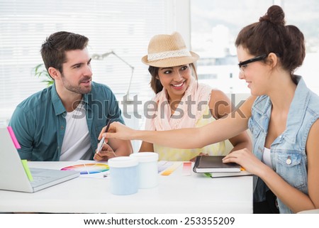 Smiling colleagues speaking together at desk in the office