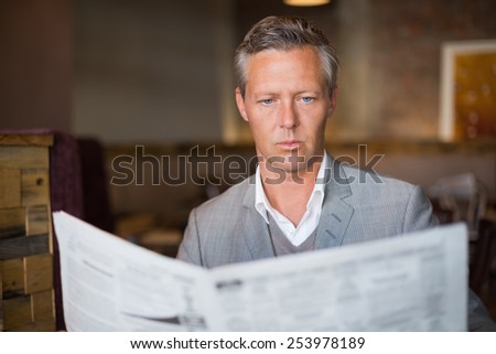 Handsome businessman reading the newspaper at the cafe