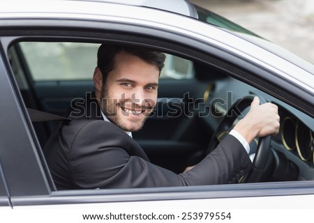 Happy businessman in the drivers seat in his car