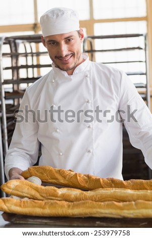 Baker looking at freshly baked baguettes in the kitchen of the bakery