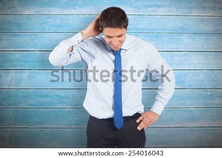 Thinking businessman scratching head against wooden planks