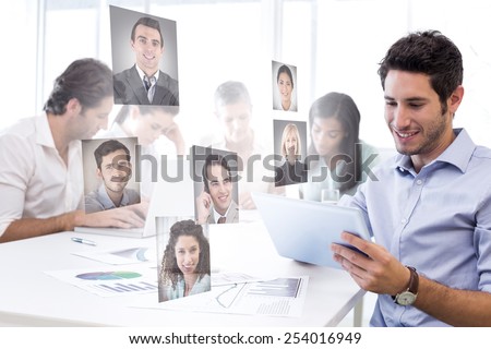 Attractive businessman using a tablet at work against profile pictures