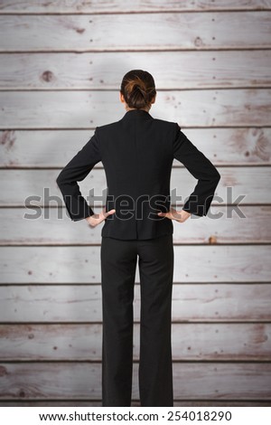 Businesswoman standing with hands on hips against wooden planks