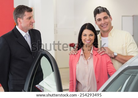 Smiling couple buying a new car at new car showroom