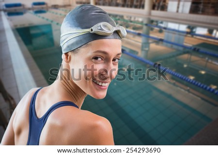Pretty swimmer by the pool smiling at camera against empty swimming pool with lane markers