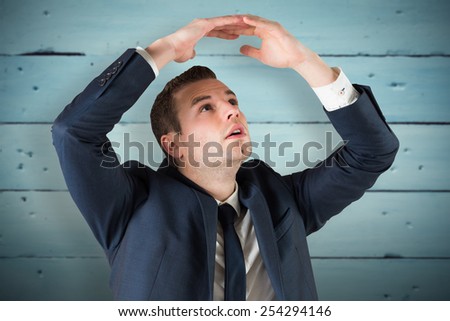 Businessman standing with hands over head against painted blue wooden planks