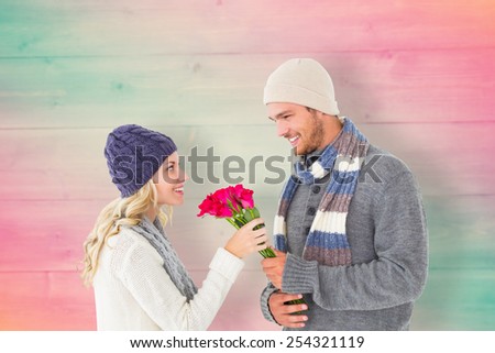 Attractive man in winter fashion offering roses to girlfriend against pink and green planks