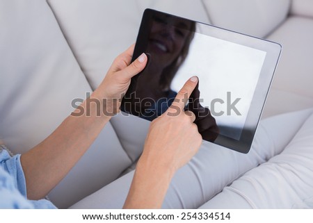 Smiling woman using tablet pc on couch at home in the living room
