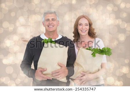 Casual couple holding grocery bags against light glowing dots design pattern