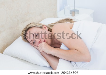 Exhausted blonde woman crying in bed at home in the bedroom