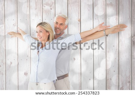 Happy couple standing with arms outstretched against light circles on grey background
