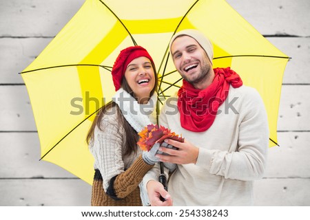 Autumn couple holding umbrella against white wood