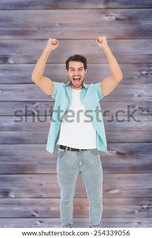Happy casual man cheering at camera against faded grey wooden planks