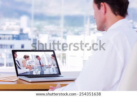Businessman looking at a laptop against serious businessman during a meeting talking to his employees