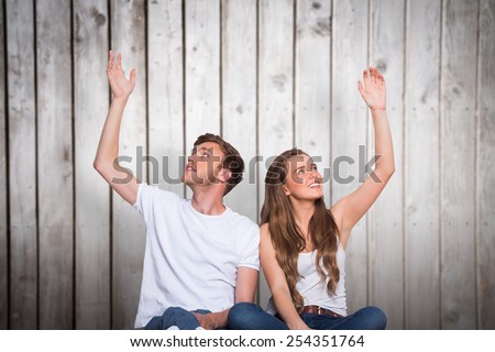 Happy young couple with hands raised against wooden planks